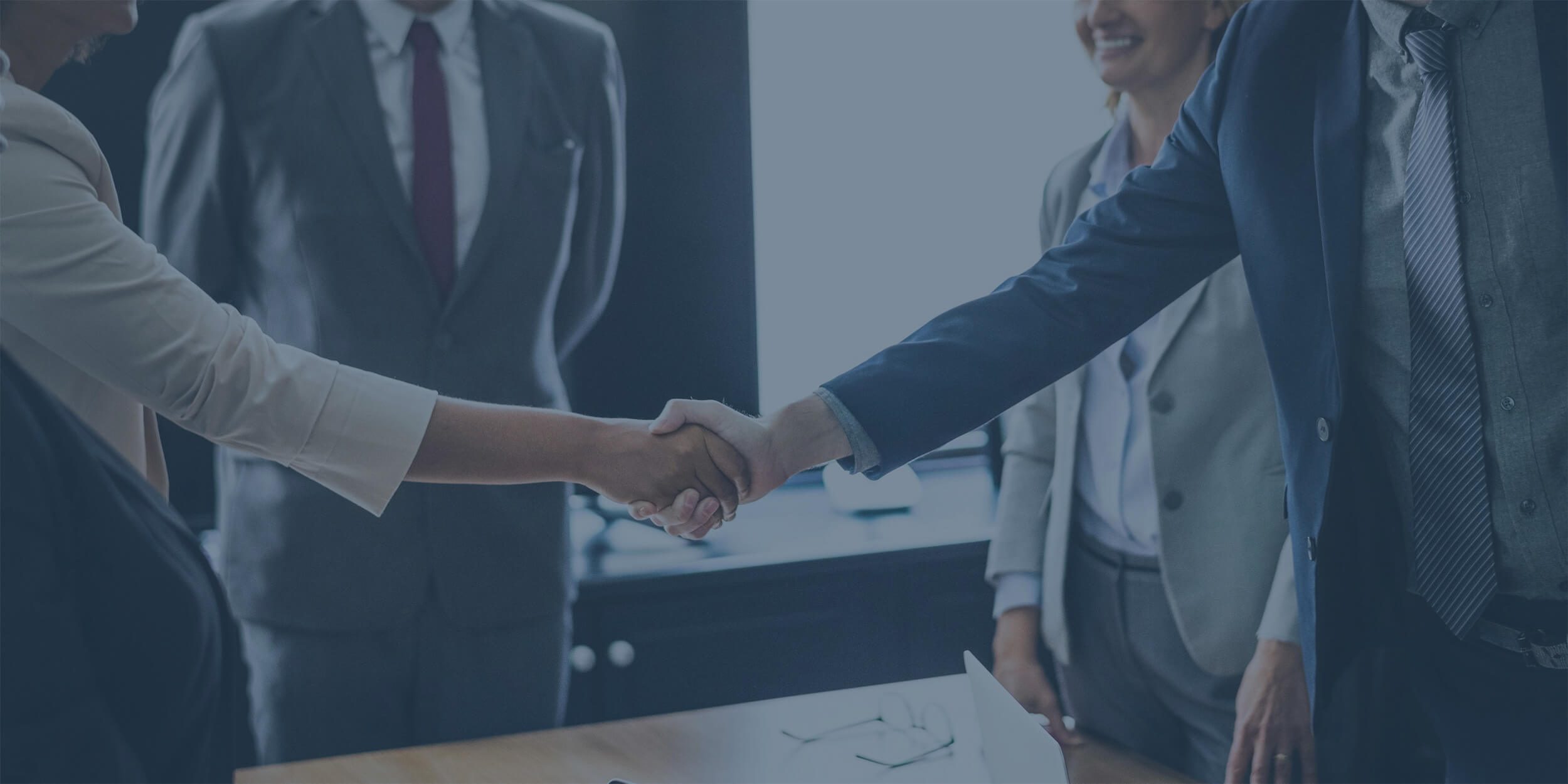 Male and female business professionals shaking hands in partnership agreement with blue tint.