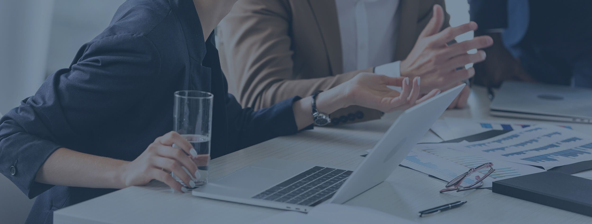 Man assisting a woman at a desk in a busy modern recruitment office. Blue Tint.