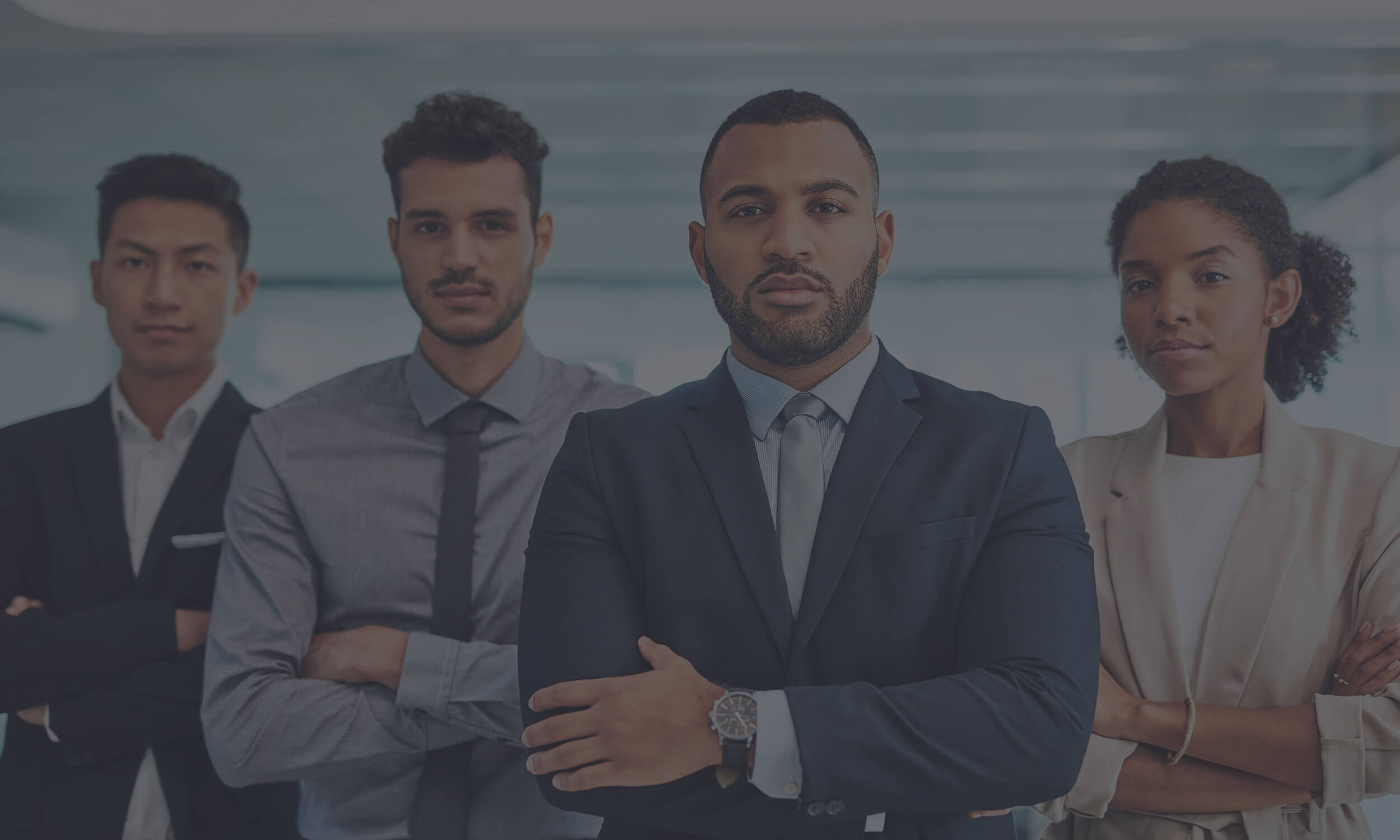 Diverse group of confident business professionals standing with arms crossed in a modern office with a dark tint over it.