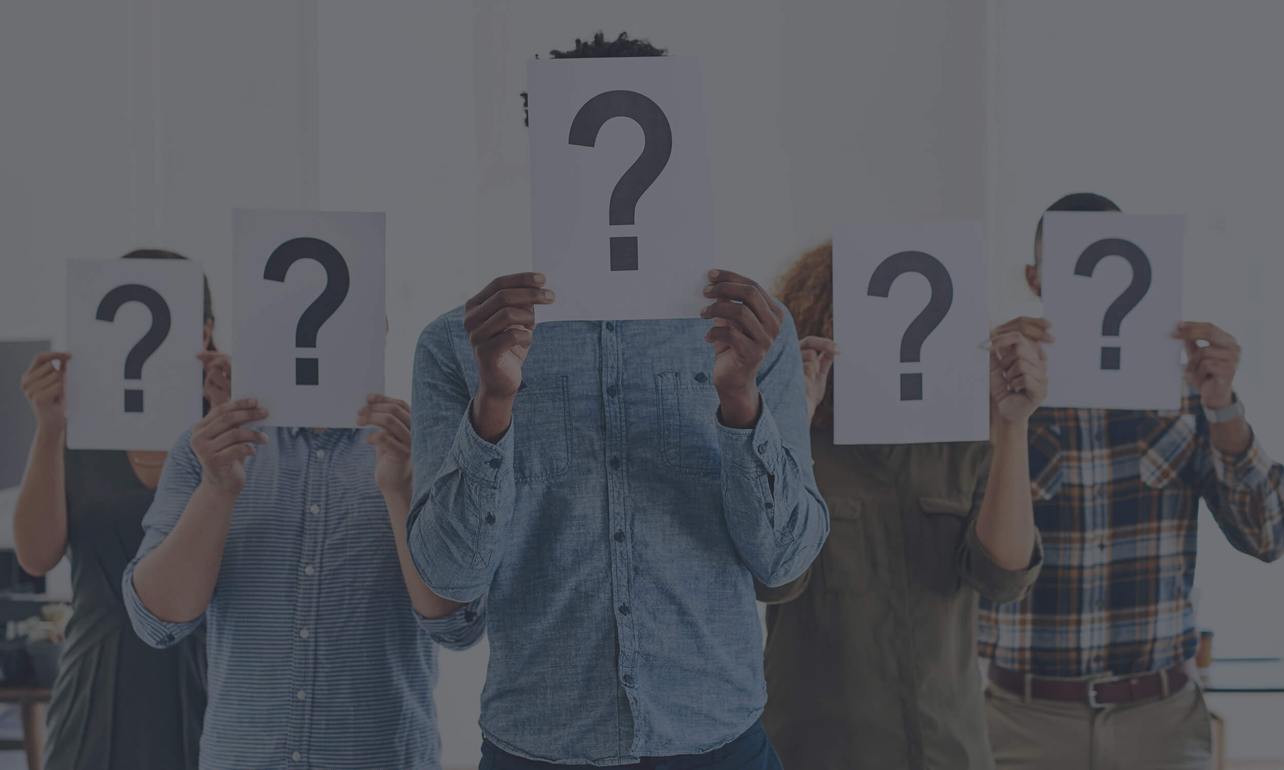 Group of diverse people holding large question mark icons, representing frequently asked questions about itris recruitment CRM and ATS with a dark overlay.